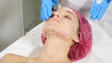 在水疗沙龙接受美容治疗的女人。 医用手套美容师戴美容面具。 皮肤护理概念